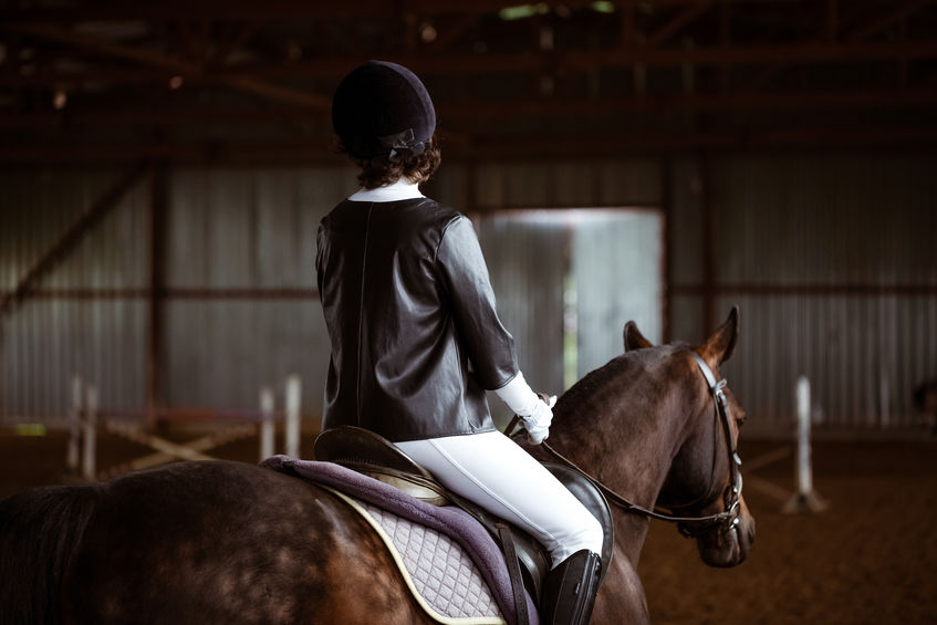 Young woman is engaged in equestrian sports, training on horseback